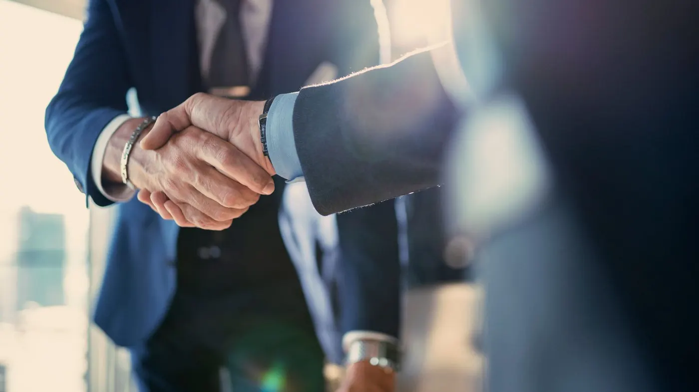 Two professionals shake hands in a quiet office.
